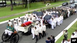 In this photo provided by the Office of Ilocos Norte Governor Imee Marcos, Imelda Marcos, in black on a wheelchair under an umbrella, the widow of the late dictator Ferdinand Marcos, and their close relatives follow the flag-draped casket of Ferdinand Mar