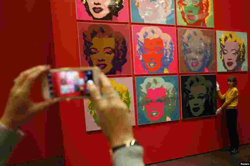 An employee poses with 10 screenprints of Marilyn Monroe by Andy Warhol as part of the exhibition, &quot;American Dream: Pop to the Present,&quot; at the British Museum in London.