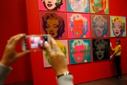 An employee poses with 10 screenprints of Marilyn Monroe by Andy Warhol as part of the exhibition"American Dream: pop to the present" at the British Museum in London, Britain, Feb. 10, 2017.