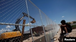 A child looks at U.S. workers building a section of the U.S.-Mexico border wall at Sunland Park, U.S. opposite the Mexican border city of Ciudad Juarez, Mexico, Aug. 26, 2016. Picture taken from the Mexico side of the U.S.-Mexico border. 
