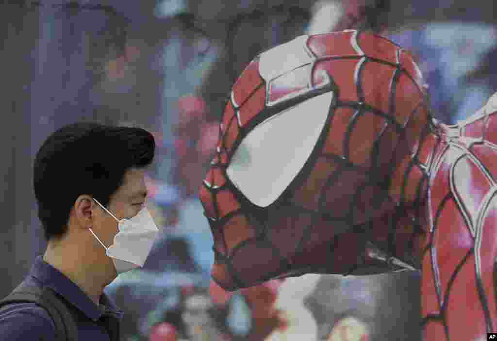 Seorang pria yang mengenakan masker sebagai pencegahan terhadap virus Middle East Respiratory Syndrome (MERS) berjalan melewati poster Spiderman di Seoul, Korea Selatan.