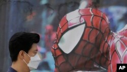 Seorang pria Korea Selatan mengenakan masker pent-up hidung dan mulutnya untuk tindakan preventive terhadap virus MERS, melewati poster pagelaran musik bergambar Spider-Man di Seoul, Korea Selatan (10/6). 