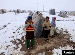 FILE - Internally displaced Afghan children stand outside their shelter in the cold at a refugee camp on the outskirts of Herat city, Afghanistan.