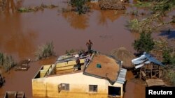 Um homem em cima de uma casa numa área completamente inundada, depois da passagem do ciclone Idai. Distrito de Buzi, Beira, Moçambique, 22 de Março, 2019. 