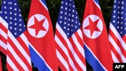 Bendera Korea Utara dan AS berdampingan di lokasi pertemuan pemimpin Korea Utara Kim Jong Un dengan Presiden AS Donald Trump untuk KTT AS-Korea Utara, di Hotel Capella di Pulau Sentosa di Singapura pada 12 Juni 2018. (Foto: AFP)