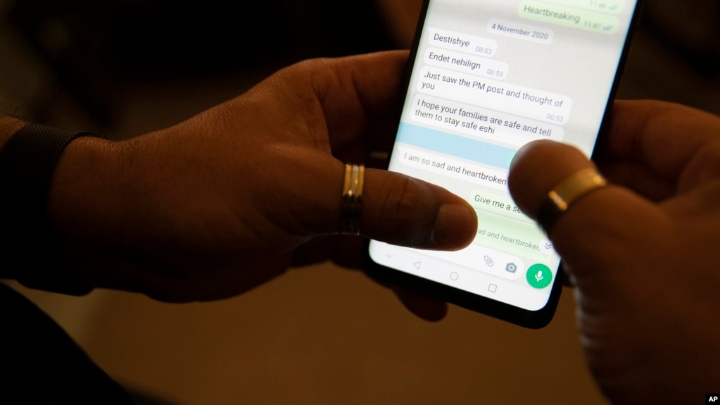 FILE - Desta Haileselassie looks at messages on his phone in Stockholm, Sweden, Oct. 18, 2021. Cut off from Tigray due to a communications blackout, Desta has been compiling a list of Tigrayan victims of war.