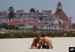 In this May 22, 2012 photo, a couple enjoys the sun and sand on Coronado Beach in California.