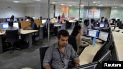 In this file photo, employees of ISGN work at their stations inside the company headquarters in the southern Indian city of Bangalore, India.