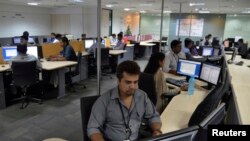 In this file photo, employees of ISGN work at their stations inside the company headquarters in the southern Indian city of Bangalore, India.