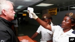 Petugas kesehatan memeriksa suhu tubuh penumpang yang memasuki bandara internasional Lagos, Nigeria (20/10).