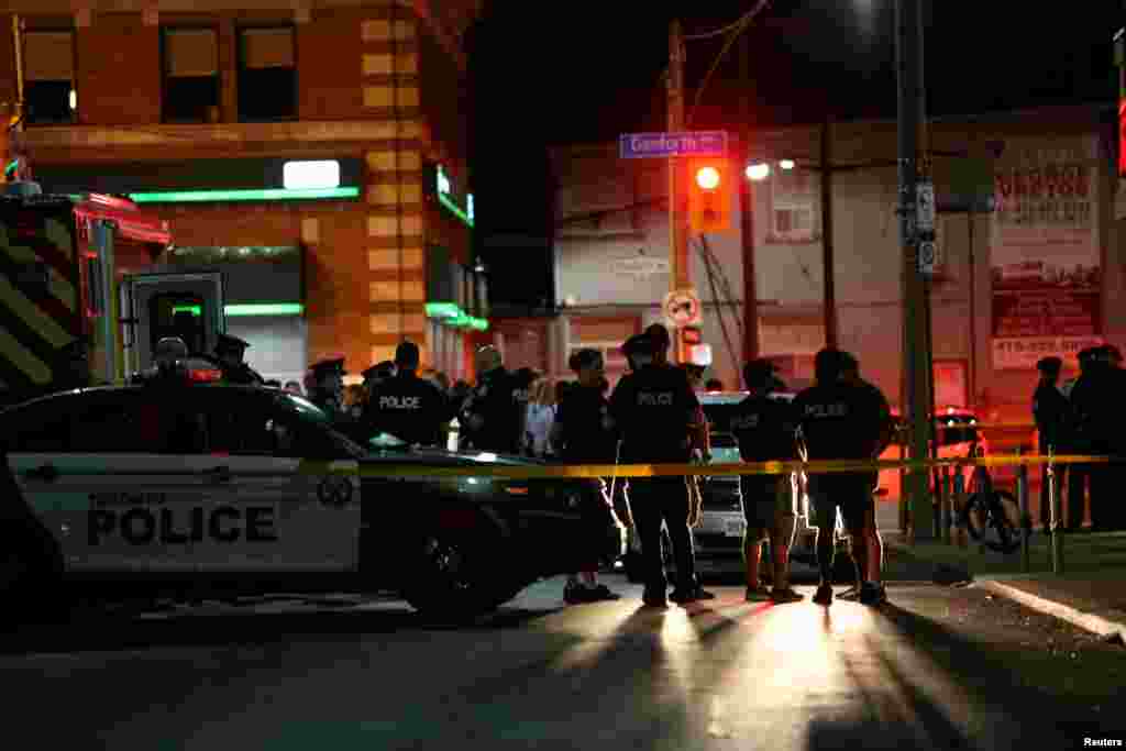 캐나다 토론토 총격 난사 사건 현장 주위에 경찰들이 서 있다. 이 사건으로 2명이 숨지고 12명이 다쳤다.