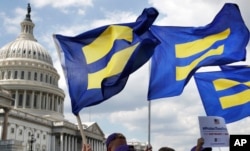 FILE - People with the Human Rights Campaign hold up "equality flags" during an event on Capitol Hill in Washington, July 26, 2017, in support of transgender members of the military.