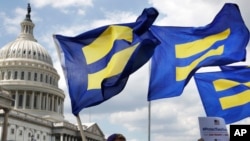 FILE - In this July 26, 2017, photo, people with the Human Rights Campaign hold up "equality flags" during an event on Capitol Hill in Washington, in support of transgender members of the military.