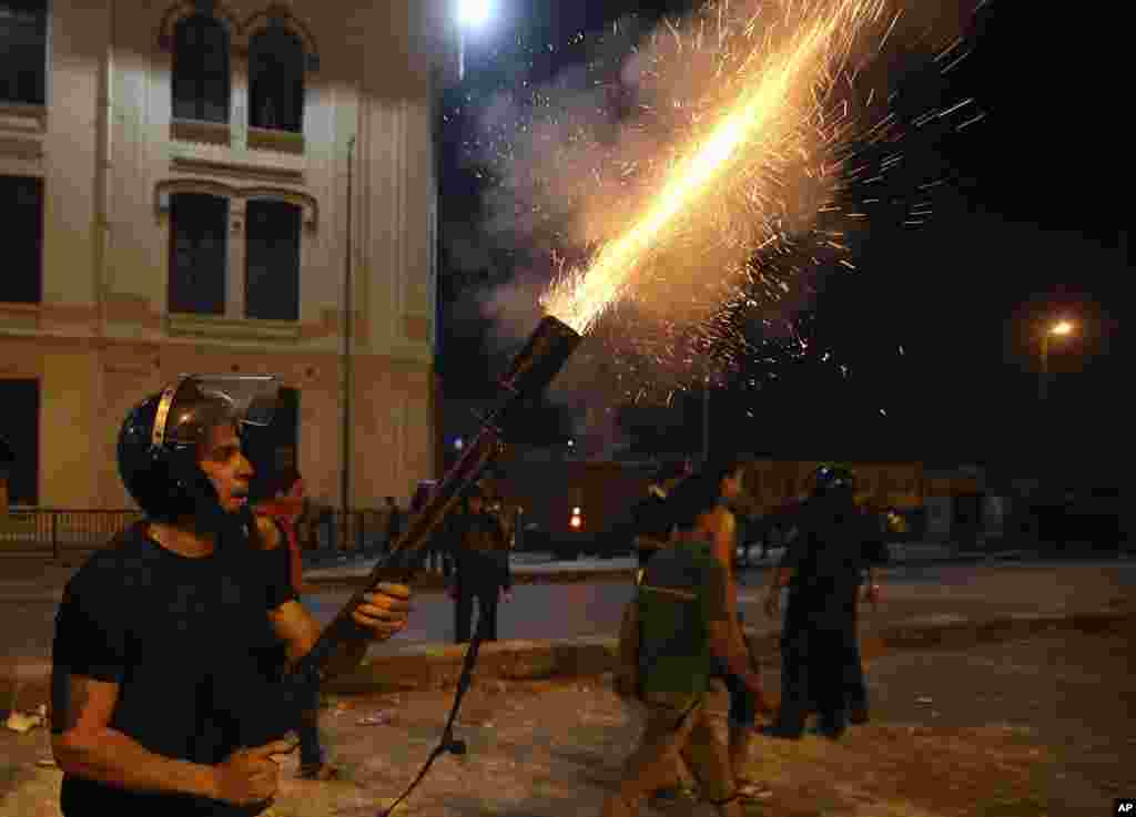 Pasukan keamanan Mesir menembakkan gas air mata ke arah pendukung Mohamed Morsi dalam bentrokan di pusat kota Kairo (15/7). (AP/Hussein Mala)