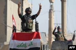 Members of Iraq's elite counter-terrorism service flash the "V" for victory sign, Dec. 29, 2015 in the city of Ramadi, the capital of Iraq's Anbar province, about 110 kilometers west of Baghdad, after Iraqi forces recaptured it from the Islamic State (IS).