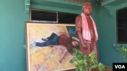 A statue of Kem Ley is displayed in front of a painting that depicts the scene of his death at Caltex station last year, Takeo province, Cambodia, July 02, 2017. (Hul Reaksmey/VOA Khmer)