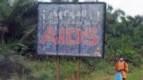 FILE - A man stands next to an AIDS billboard as he cleans a street in Yaounde, Cameroon, March 20, 2009. 
