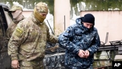 A Ukrainian sailor, right, is escorted by a Russian intelligence officer to a court room in Simferopol, Crimea, Nov. 27, 2018. 