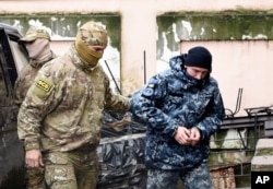 A Ukrainian sailor, right, is escorted by a Russian intelligence officer to a court room in Simferopol, in Russia-annexed Crimea, Nov. 27, 2018.