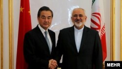 中國外長王毅（左）在北京和到訪的伊朗外長扎里夫握手。（2016年12月5日） 