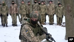 An instructor trains members of Ukraine's Territorial Defense Forces, volunteer military units of the Armed Forces, in a city park in Kyiv, Ukraine, Saturday, Jan. 22, 2022. (AP Photo/Efrem Lukatsky)