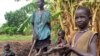 John Kawai Lam, 8, right, plays with a non-functioning automatic rifle that he found buried in the soil where he and his mother, Tabitha Nyanyun Ruach, were farming in May of 2014 in Unity state. New fighting erupted in Unity and Upper Nile states in January 2015, as South Sudan's conflict entered a second year. (AP Photo/Josphat Kasire)