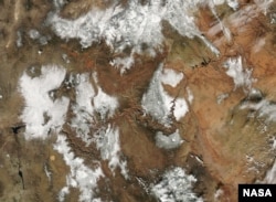 Snow across the burnt-orange rock of the Grand Canyon seen from space.