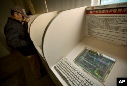 A Chinese investor uses a computer terminal to check stock prices in a brokerage house in Beijing, Jan. 29, 2016.
