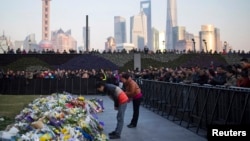 People bow during a memorial ceremony for people who were killed in a stampede incident during a New Year's celebration on the Bund, in Shanghai, Jan. 2, 2015.
