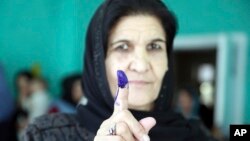 An Afghan woman shows her inked finger after casting her vote at a polling station during the Parliamentary elections in Kabul, Afghanistan, Oct. 20, 2018. 