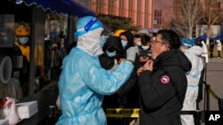 A man gets a swab for the COVID-19 test to meet traveling requirements at a mobile coronavirus testing facility outside a commercial office buildings in Beijing, Jan. 16, 2022.