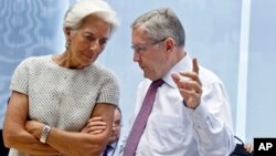 Managing Director of the International Monetary Fund Christine Lagarde speaks with Klaus Regling, chair of the European Financial Stability Facility, during a meeting of eurozone finance ministers at the EU Lex building in Brussels, July 11, 2015. 