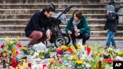 A family lights a candle at a memorial site at the Place de la Bourse in Brussels, March 27, 2016.