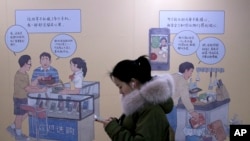 2019年1月3日在北京一个地铁站，女子看着手机，走过推广iPhone的壁画。