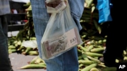 A vendor holds the bank notes in a plastic bag, at a market in Caracas, Venezuela.