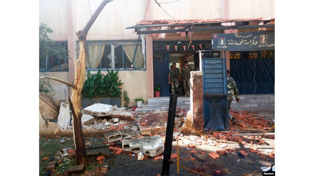 A handout photo distributed by Syria's national news agency SANA shows soldiers around wreckage in after twin suicide bombs tore through a school at Akrama neighborhood in Homs city, Oct. 1,2014.