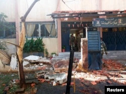 A handout photo distributed by Syria's national news agency SANA shows soldiers around wreckage in after twin suicide bombs tore through a school at Akrama neighborhood in Homs city, Oct. 1,2014.