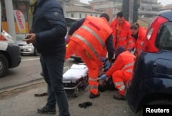 Medical personnel take care of an injured person who was hit by gunfire from a vehicle in Macerata, Italy, Feb. 3, 2018.