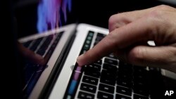 FILE - A guest looks at the Touch Bar on a MacBook computer shown in a demo room following the announcement of new products at Apple headquarters, in Cupertino, California, Oct. 27, 2016.