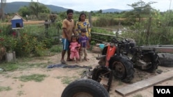 Kea Teav and her family stand in front of a two-wheeled tractor that was burnt down by a member of the Wildlife Alliance team in Krakor district, Pursat province, Cambodia, August 5, 2020. (Sun Narin/VOA Khmer)