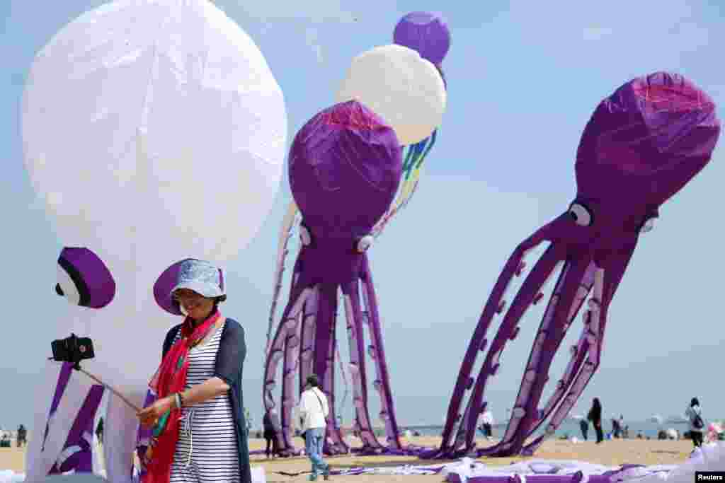 A person takes selfies with kites at a local kite festival in Langfang, Shandong province, China, April 15, 2017.