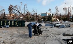 A man rests after pulling a dolly through sand as he helps retrieve belongings from his brother-in-law's destroyed home in the aftermath of Hurricane Michael in Mexico Beach, Florida, Oct. 17, 2018.