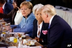 German Chancellor Angela Merkel watches as President Donald Trump talks with IMF Managing Director Christine Lagarde during the Gender Equality Advisory Council breakfast during the G-7 summit in Charlevoix, Canada, June 9, 2018.