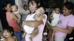 Filipino mothers carry their babies outside a health center in Taguig, south of Manila, Philippines.