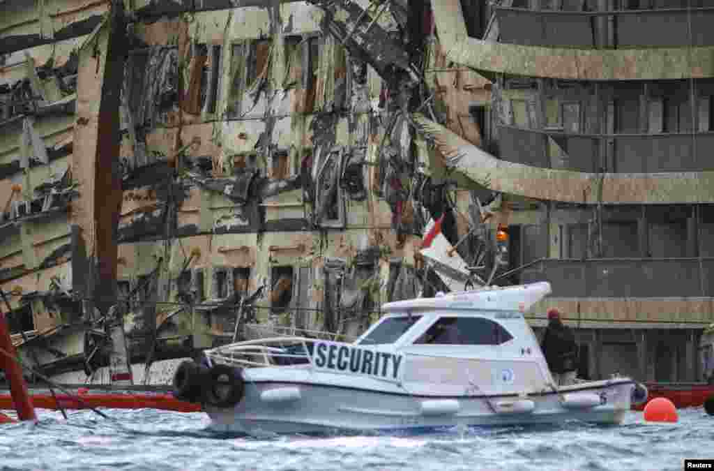 The damaged side of the capsized cruise liner Costa Concordia is visible after the ship was righted outside Giglio harbor, Italy, Sept. 17, 2013. 