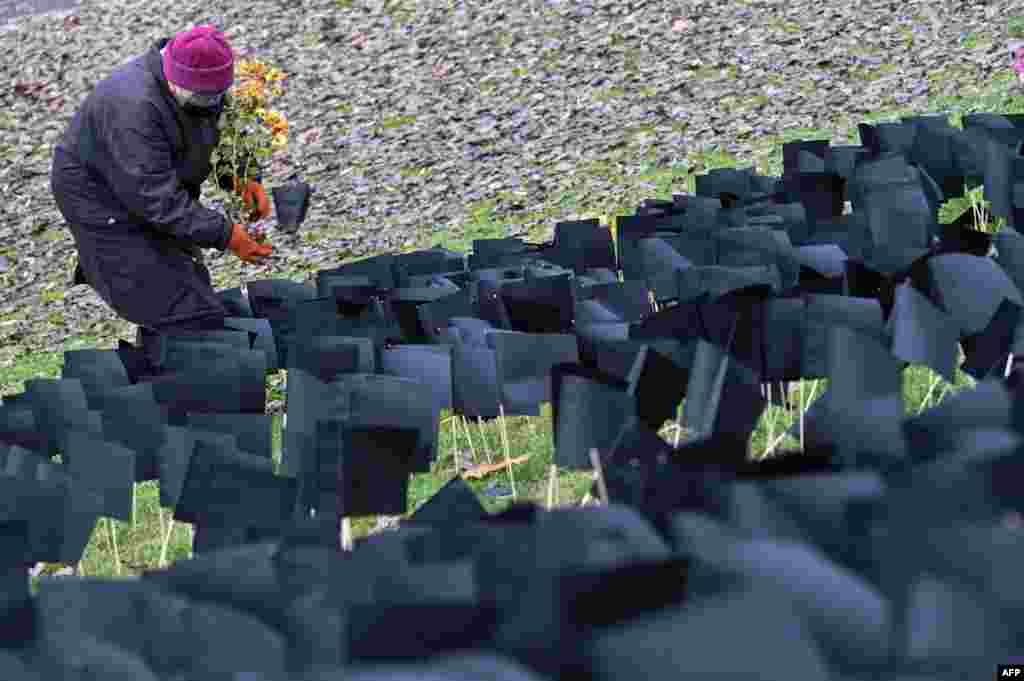 An elderly woman places flowers in front of several thousand black paper flags set up at the "Bikas" (Bull) Park in Budapest, Hungary, in honor of the people who have died during the coronavirus pandemic.