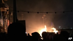Restoran-restoran kecil terbakar akibat serangan bom mobil di distrik Syiah di Baghdad (4/12). (AP/Ali Abdul Hassan)