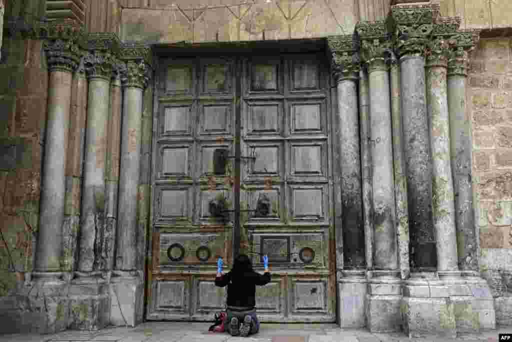 A woman prays in front of the Church of the Holy Sepulchre in the Old City of Jerusalem following the closure of the city for non-residents as a measure to contain the spread of the new coronavirus.