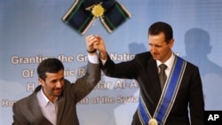 Iranian President Mahmoud Ahmadinejad, left, holds up the hand of his Syrian counterpart Bashar al-Assad after he was awarded Iran's highest national medal in a ceremony in Tehran, Iran, 2 Oct 2010