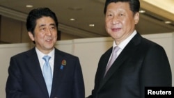 Japan's Prime Minister Shinzo Abe (L) shakes hands with China's President Xi Jinping at the start of their bilateral meeting on the side lines of the Asian-African Conference in Jakarta, in this photo released by Kyodo, April 22, 2015. 